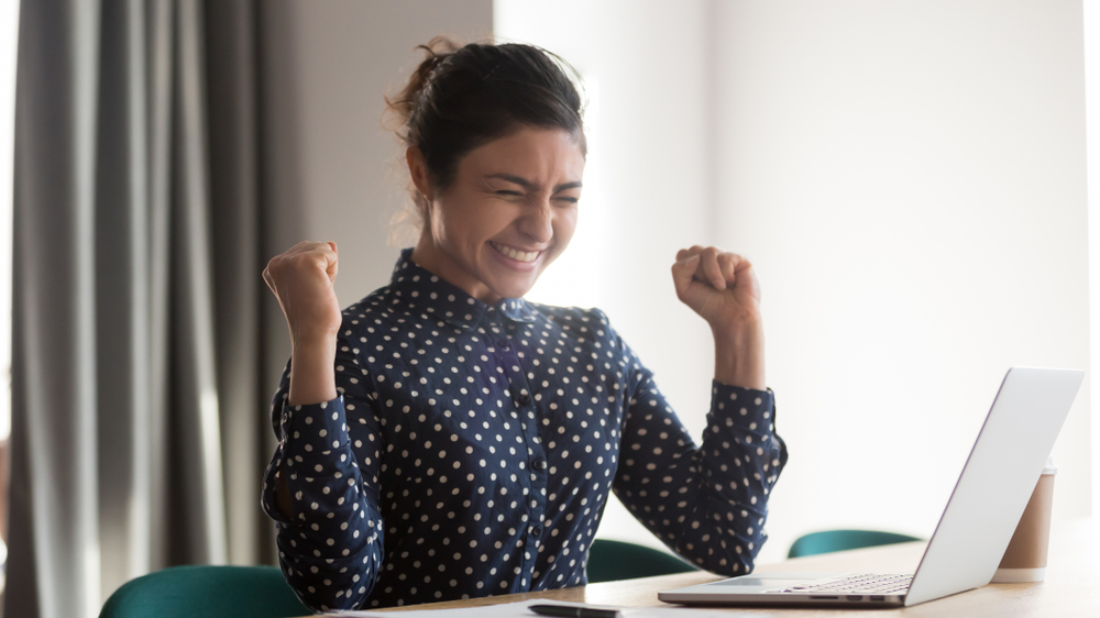 Foreign worker celebrating success after getting a job in Japan while using a laptop
